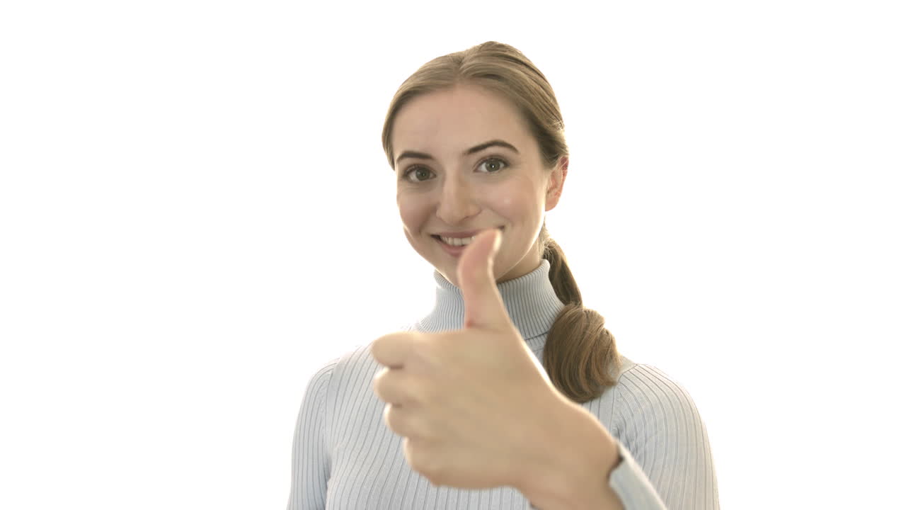 Smiling woman in studio giving likes - thumbs up. Isolated on white background with copy space
