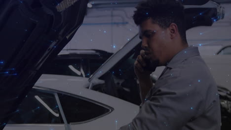 male mechanic making smartphone call while inspecting open hood in garage, showing digital overlays