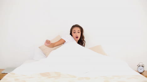 mujer joven despertando y bostezando en su cama por la mañana