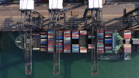 multiple gantry cranes handling a giant container vessel which is bunkering fuel in the mean time