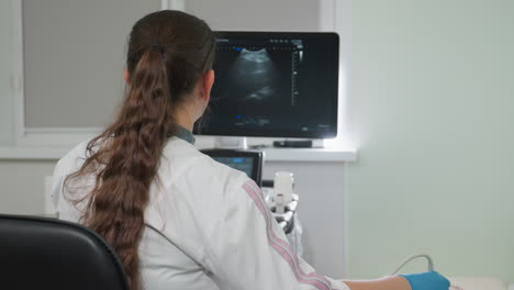 female lab technologist focuses intently on monitor displaying patient internal organ movement during diagnostic procedure using advanced medical equipment in bright clinical setting with precision