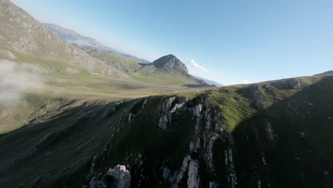 clouds flowing over rocky mountains in spain, aerial fpv view