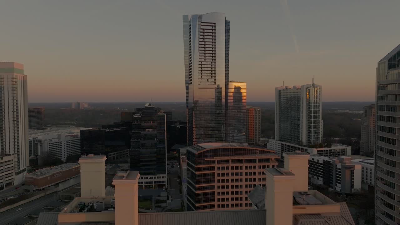 Cena de drone revelando o horizonte comercial e residencial de Buckhead ao pôr do sol