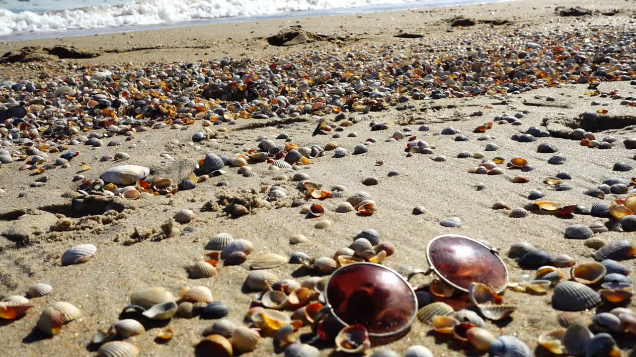 Sunglasses on the sandy beach. Slow motion