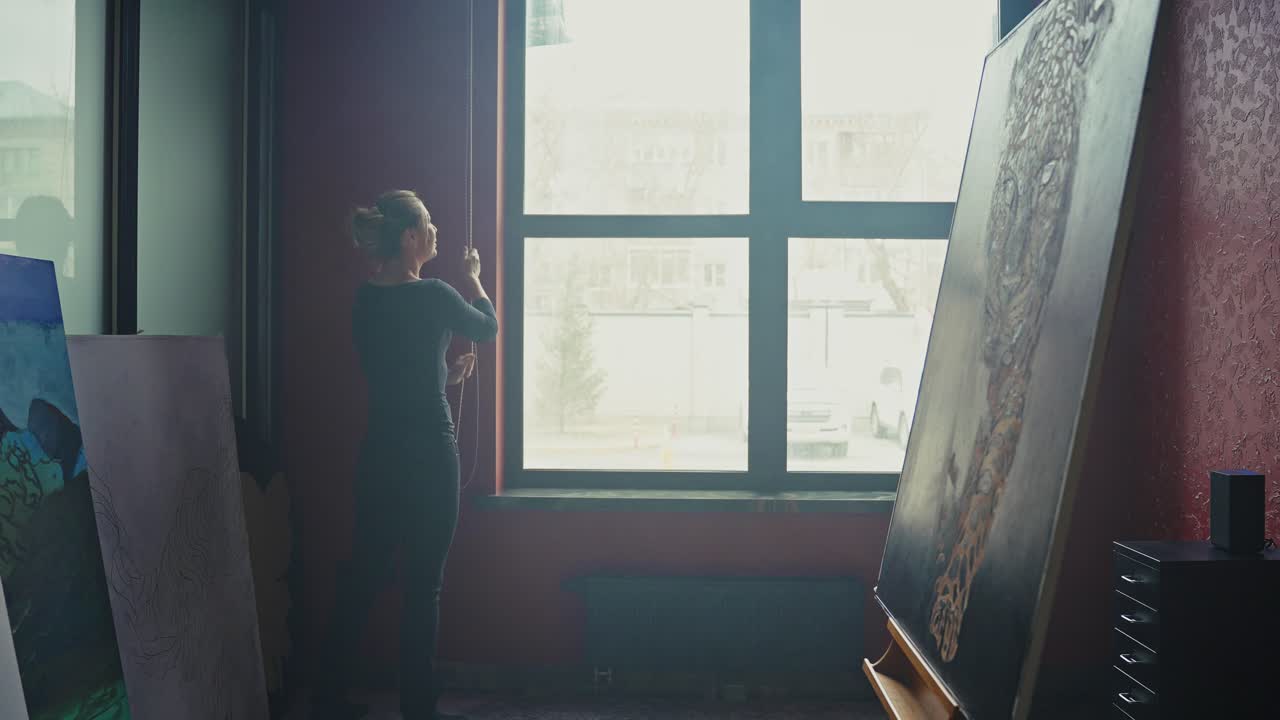 Woman Artist Adjusting Blinds in an Art Studio