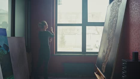woman artist adjusting blinds in an art studio