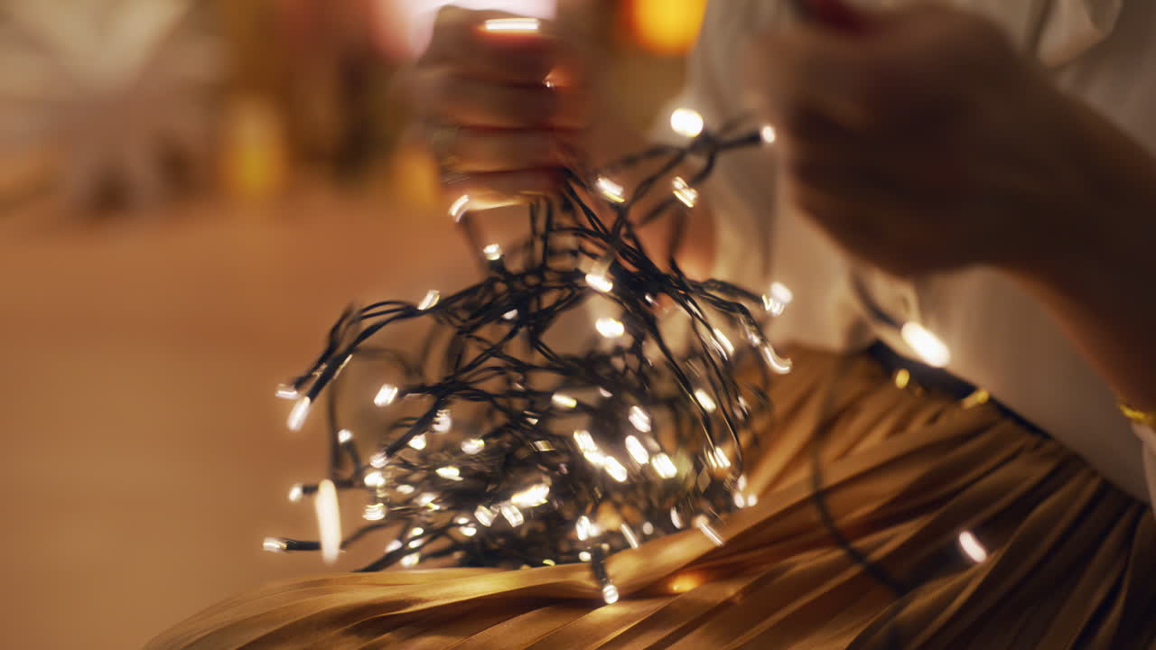 una mujer con un interior cálido desenredan las luces de navidad.