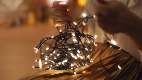 woman in warm interior untangles christmas lights