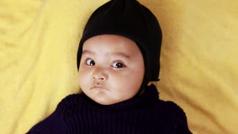 infant boy in black outfit lying cute facial expression at indoor from top angle