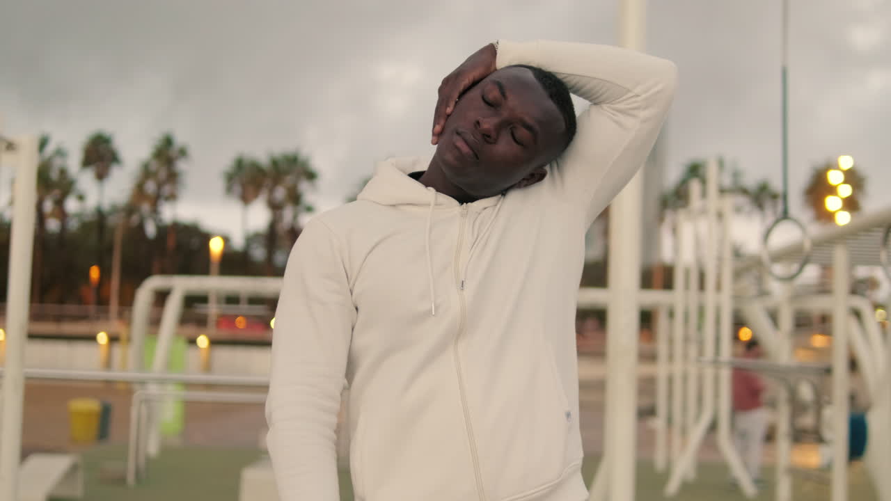 Young Black Man Stretching Neck and Wrists in Outdoor Calisthenics Park