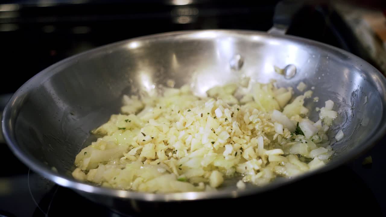 Adding thyme to onions in a pan of olive oil Preparing ingredients to make vegan beyond meatballs with spaghetti and meat sauce
