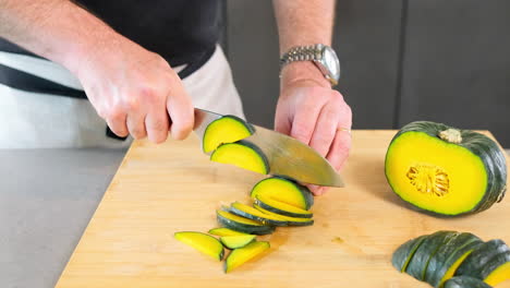 chef masculino cortando grandes rodajas de calabaza verde en la cocina con el cuchillo afilado