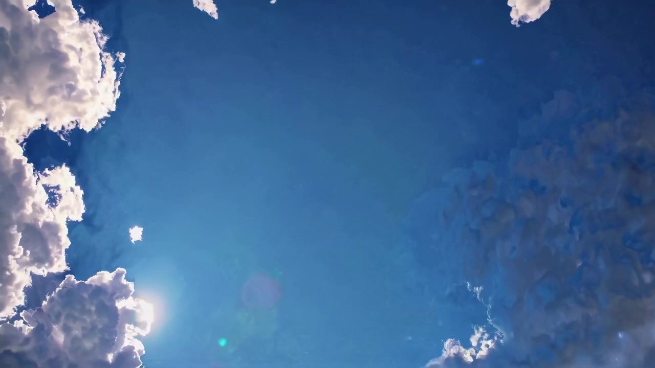 澄み切った青空にふわふわの白い雲が浮かび、太陽のフレアが差し込むタイムラプス