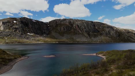 Beautiful-areal-crane-shot-above-tundra,-revealing-majestical-mountains-and-crystal-clear-blue-water-in-Gandajavri-lake-in-far-north-of-Norway