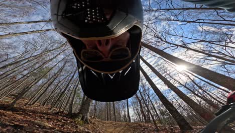 mtb rider pov pushing bike uphill on fall trail and looking at camera multiple times