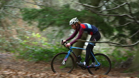 young man cross-country cycling between trees in a forest, shot on r3d