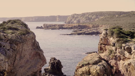 a view through a couple cliffs with rock formations and the ocean in the back