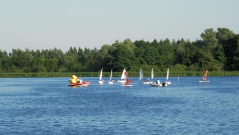 motion timelapse of opti dinghies cruising on blue lake water in kolbudy, poland on a sunny day