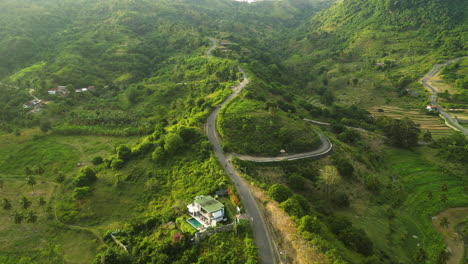 Sobrevuelo-Aéreo-Exuberante-Paisaje-Verde-En-Lombok-Montando-Motocicletas-En-Carretera-De-Montaña-Durante-El-Amanecer-Brumoso,-Indonesia