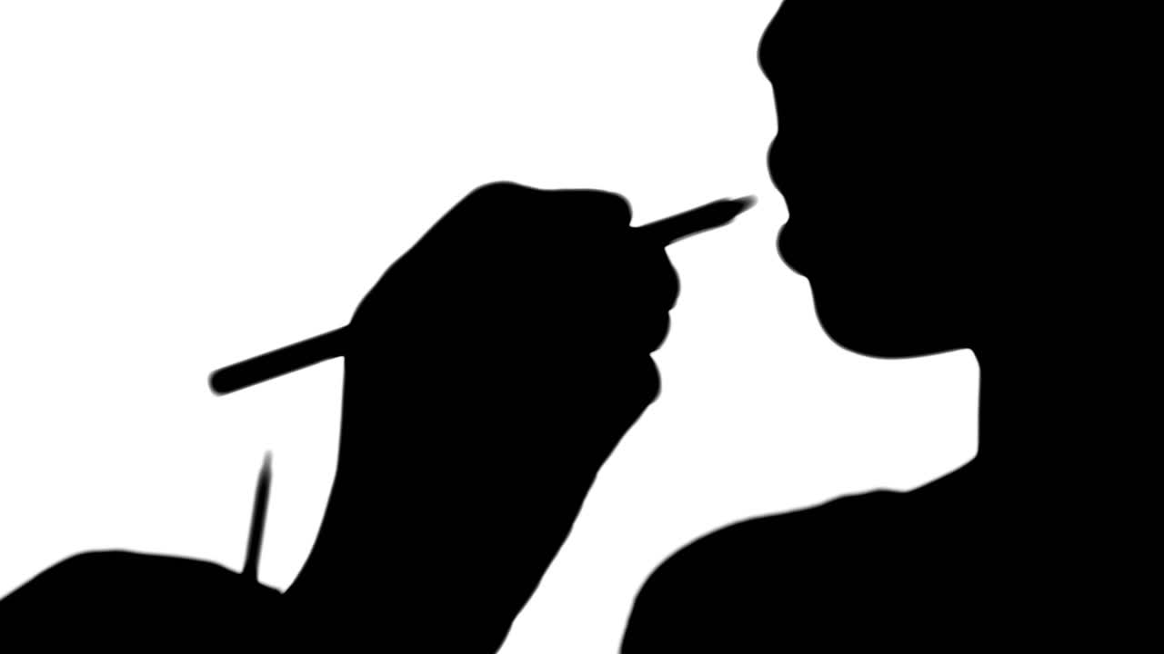 메이크업 아티스트가 모델의 얼굴에 립 글러스를 붙이고 있습니다.