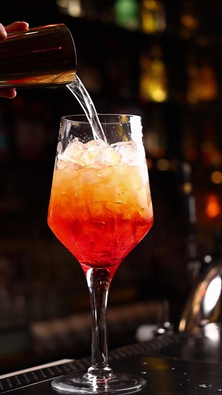 Barman che versa acqua frizzante in un cocktail Aperol Spritz
