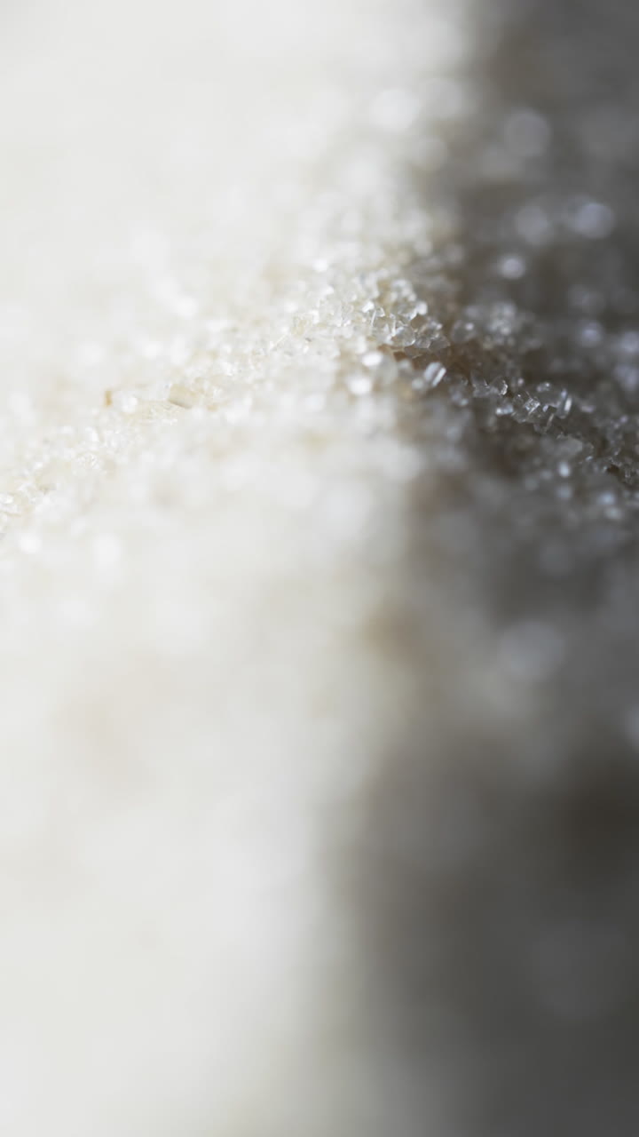 Vertical video of close up of heap of sand grains and copy space on white background