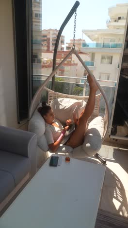 woman working on laptop in a hanging chair on a balcony