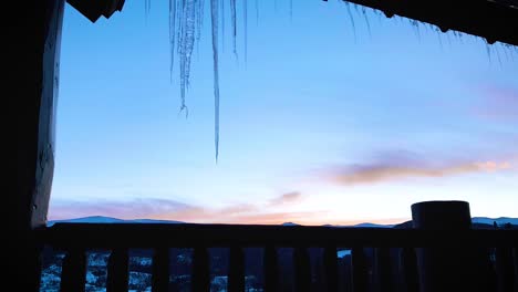 winter sunrise over mountain range time lapse from balcony with icicles