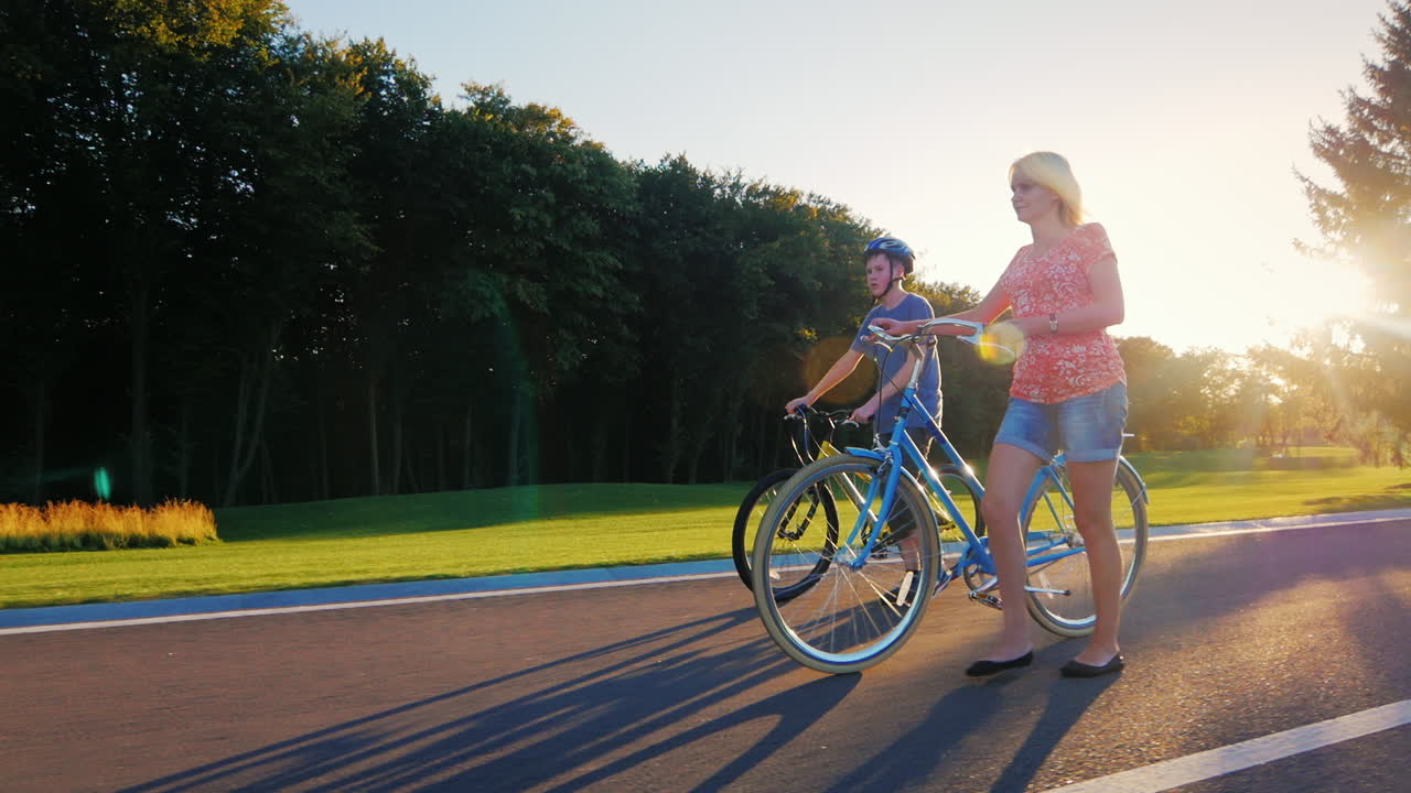 자전거 슬로우 모션으로 공원에서 산책하는 여자와 아들