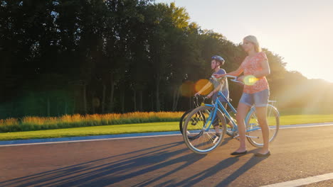 Frau-Und-Sohn,-Die-Mit-Fahrrädern-Im-Park-Spazieren-Gehen-Zeitlupe