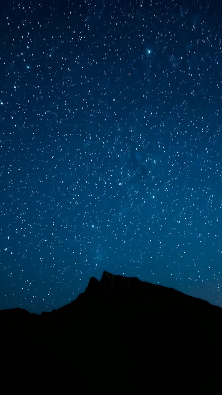 Vídeo vertical: câmera de lapso de tempo capturando a cordilheira centralizada em meio a estrelas em movimento para revelar a Via Láctea