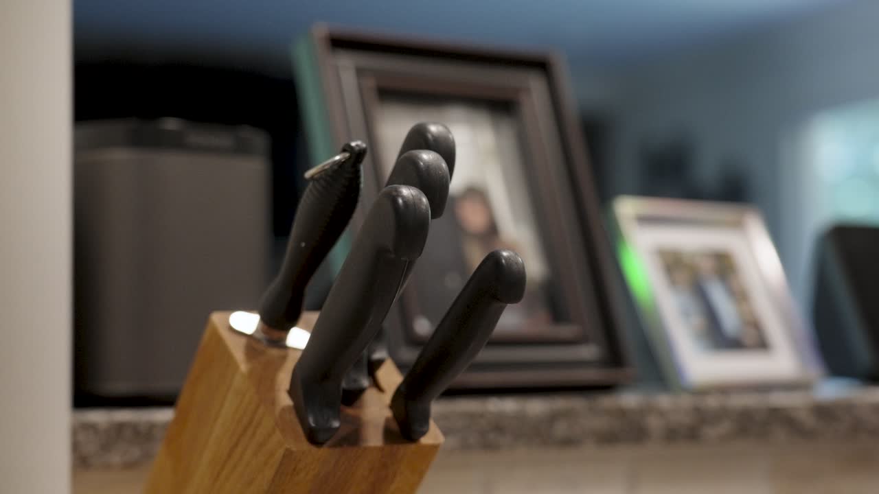 Person Reaching for Knife from Wooden Block in Kitchen