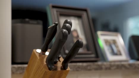 person reaching for knife from wooden block in kitchen