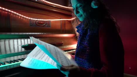 a young female wearing a santa hat plays christmas music on a beautifully decorated piano. warm lights and seasonal decor set the mood as sheet music rests on the piano.
