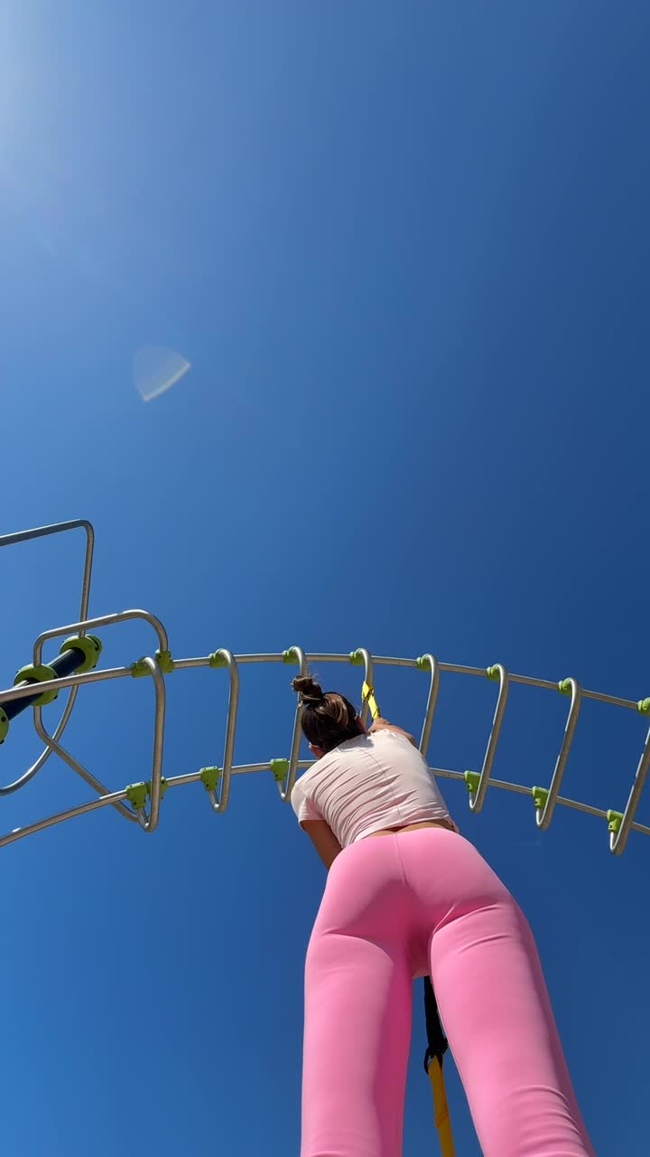 Donna che si allena con cinghie di sospensione TRX all'aperto sotto un cielo azzurro