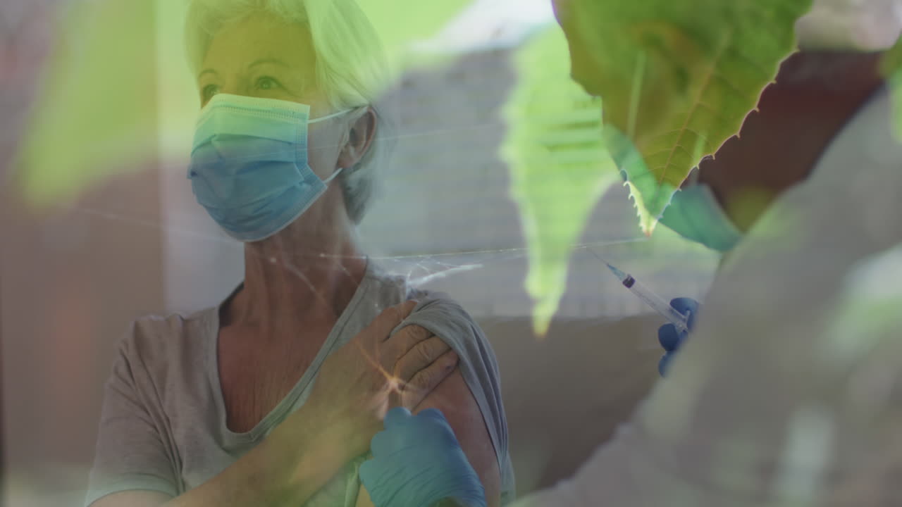 mosquito atrapado en una telaraña contra un médico masculino dando una inyección a una mujer caucásica mayor