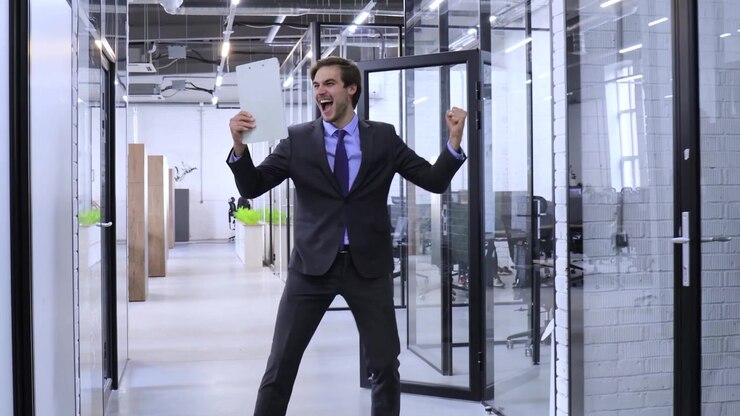 Uomo d'affari entusiasta che cammina e celebra il successo in un ufficio moderno