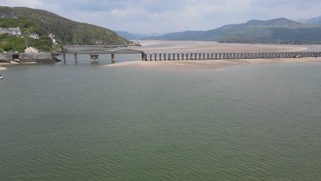 Railway-bridge-viaduct-at-Barmouth-North-Wales,-UK-seaside-town-aerial-footage