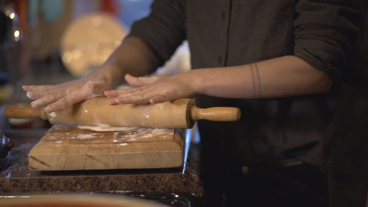 A Female Hands Using Rolling Pin To Pave A Dough Over A Wooden Board - Medium Shot
