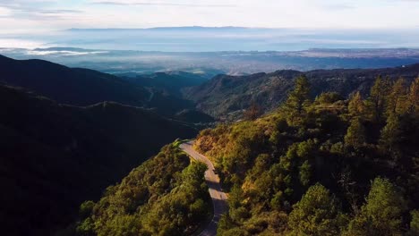 cyclist on curvy mountain road above santa barbara at dawn, drone chase