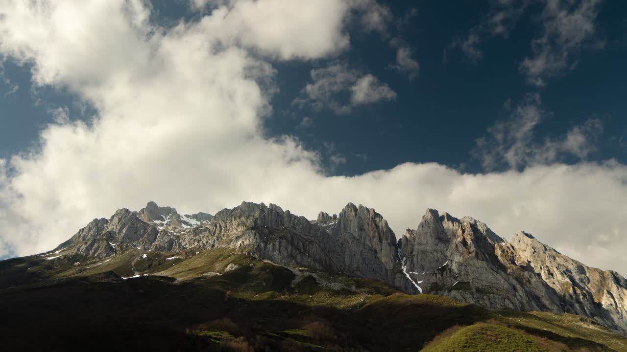 Timelapse of fast-moving clouds drifting above the majestic Picos de Europa mountains in northern Spain. Dramatic skies meet rugged peaks in a breathtaking natural scene.