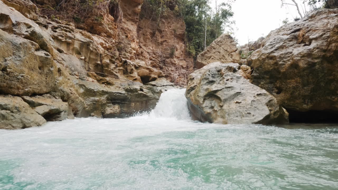moviéndose hacia una poderosa corriente fluvial y una cascada salpicando en filipinas - cámara lenta de mano dentro de un pequeño cañón