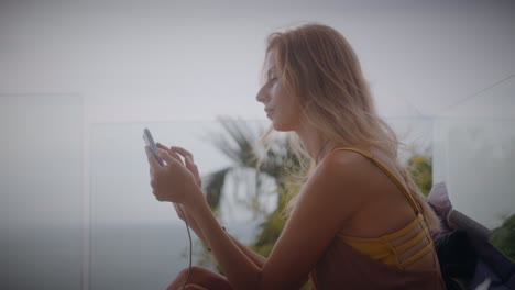 woman using phone on a balcony with ocean view