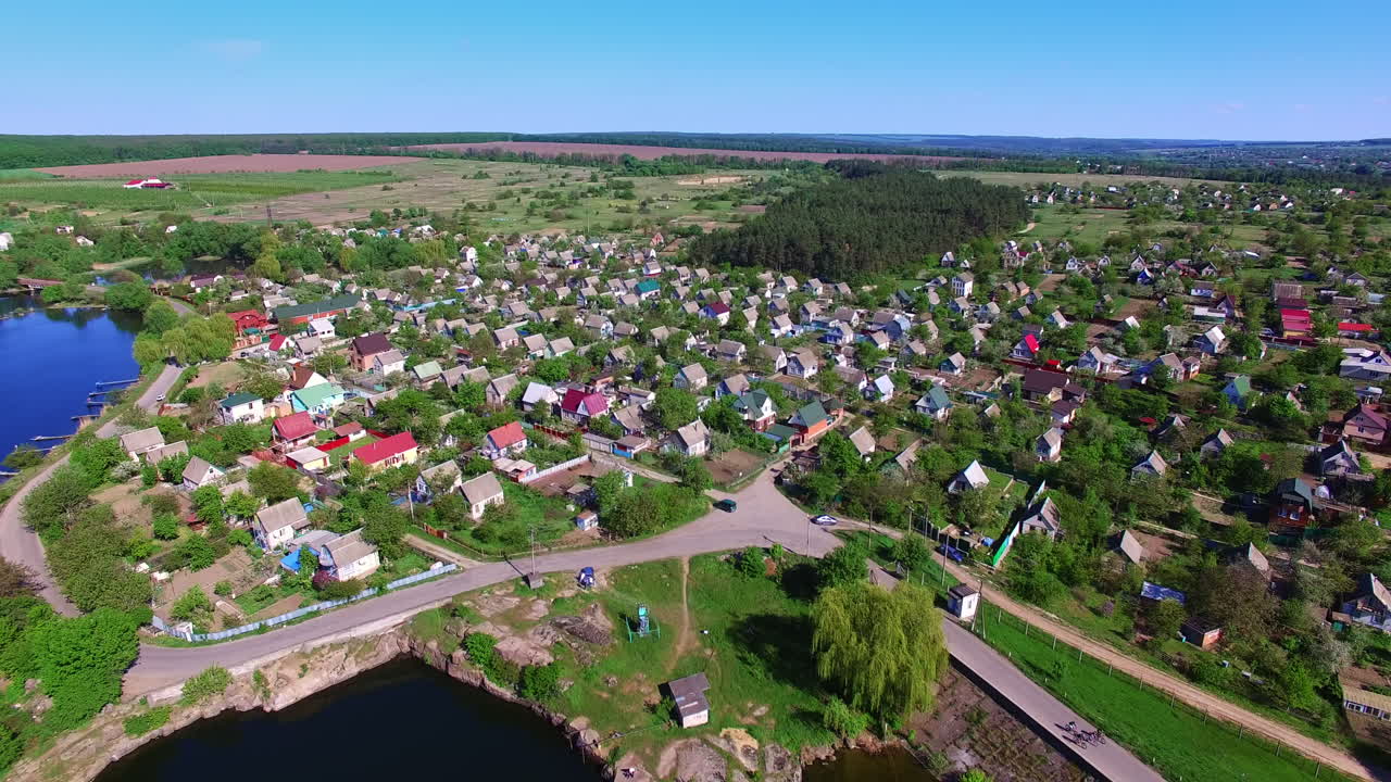 Sunny countryside landscape on a beautiful clear daytime. Lovely picturesque village locating on the bank of the river. View from top.