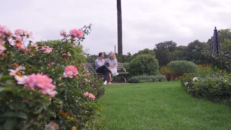 couple sitting on bench surrounded by roses and romance