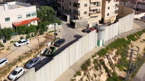 aerial view of a concrete separation barrier with a guard tower and residential buildings
