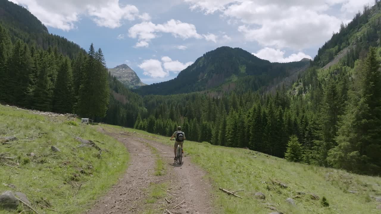 toma aérea de un ciclista con bicicleta de montaña montando en el camino entre las montañas dolomitas en verano - hermoso panorama montañoso en italia