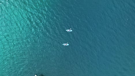 Kayaking-in-Pairs-on-the-Blue-Waters-of-Moorea,-French-Polynesia---Aerial-Drone-Shot