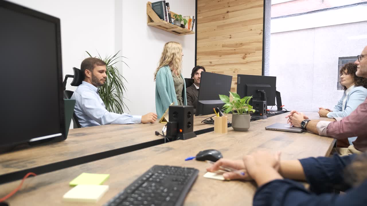Manager matura che parla con il team seduto alle scrivanie in un ufficio creativo