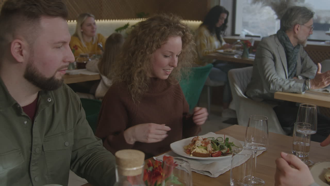 Happy Attractive Young Couple Sitting Talking Drinking Coffee Smiling Man and Woman in a Modern Cafe Happy Attractive Young Couple Sitting Talking Drinking Coffee Smiling Man and Woman in a Modern Cafe have Conversation Portrait Close up Slow Motion